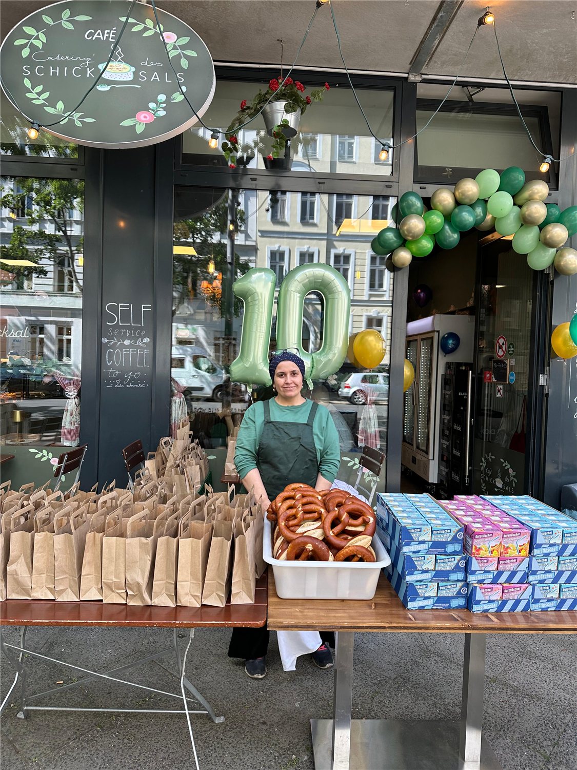 Kader vor dem Café mit Brezeln, Getränken, Geschenken und Ballons zum Jubiläum