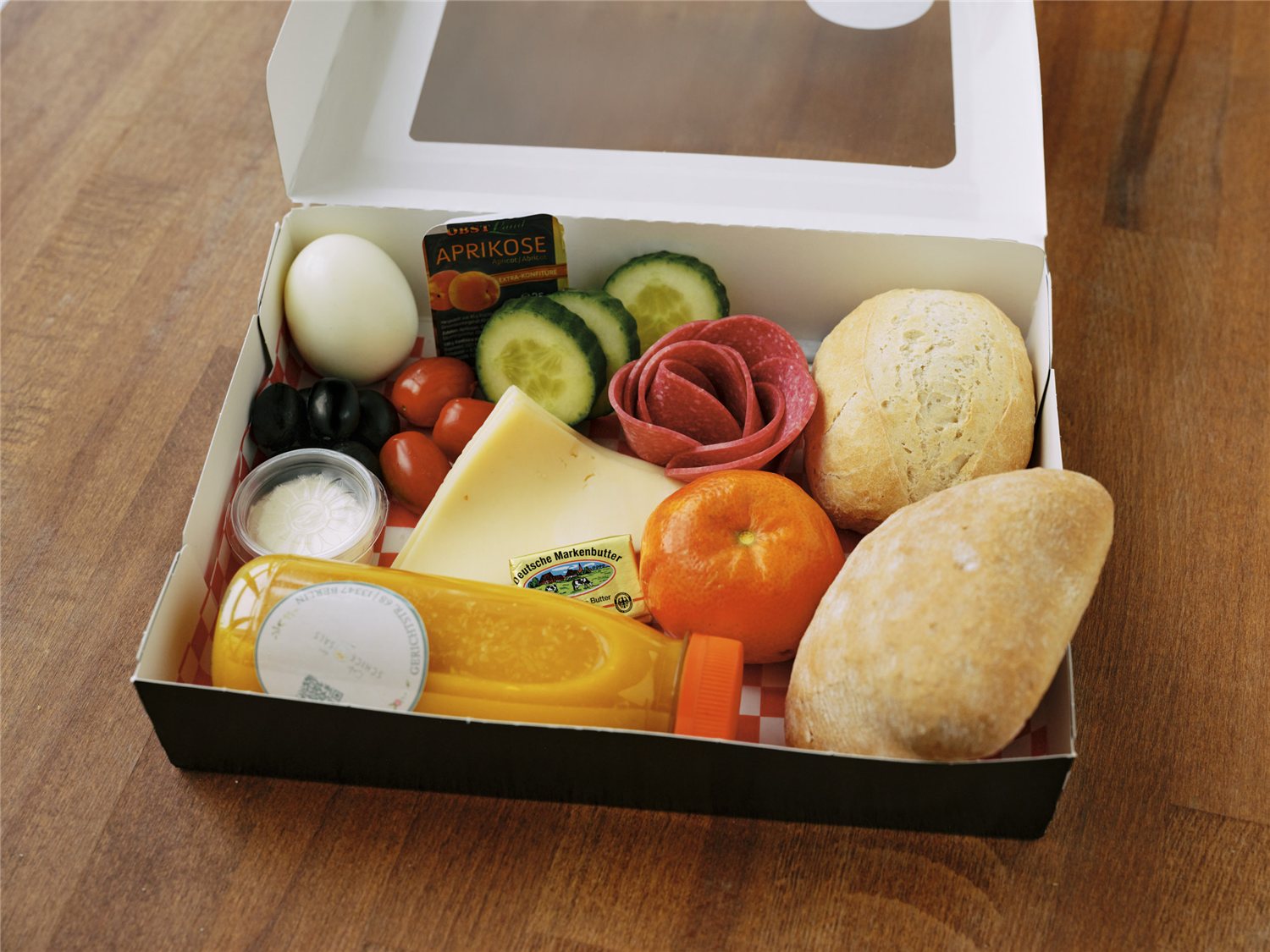 Unsere große Frühstücksbox mit Brötchen, Käse, Ei, Gemüse und Orangensaft